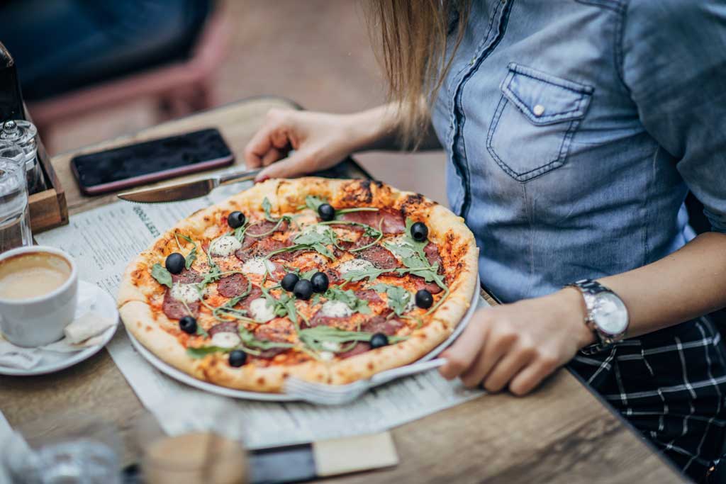 girl sitting at table with pizza